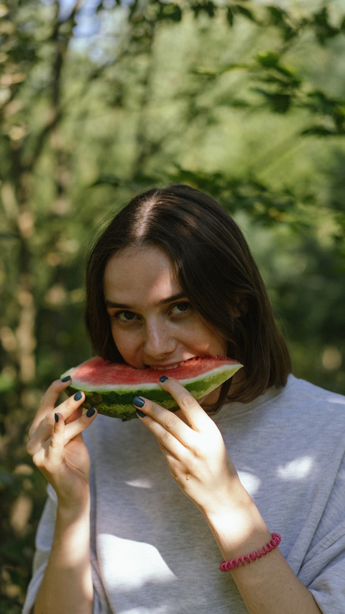 a woman is eating a piece of watermelon